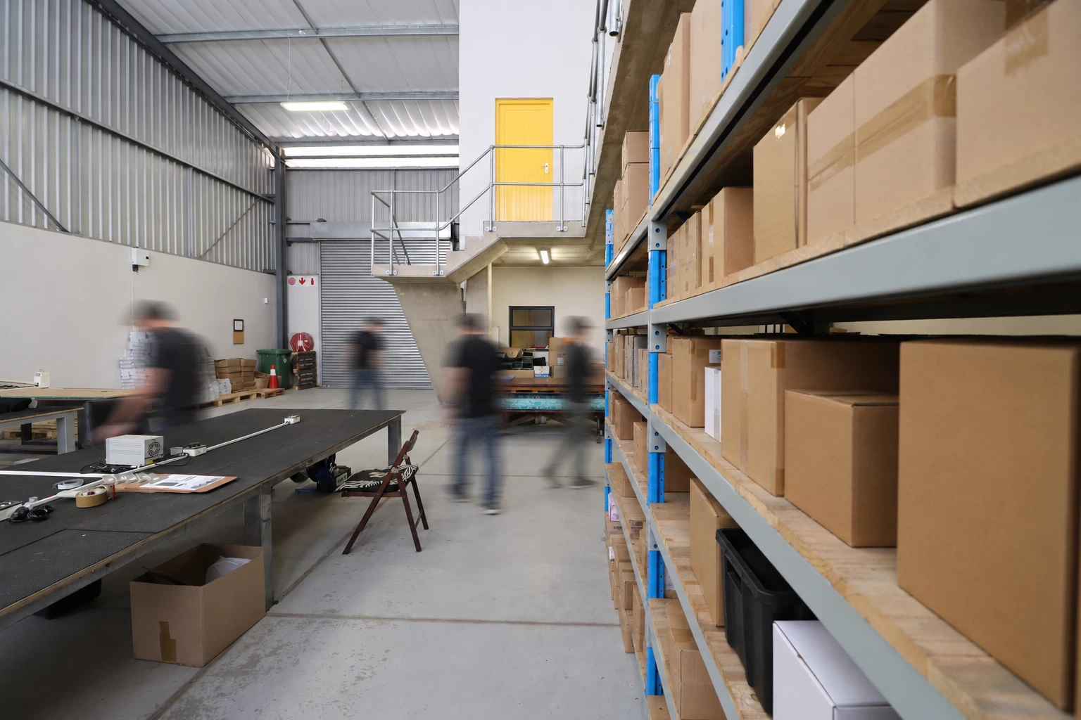 Workers moving through a busy warehouse with shelving and boxes